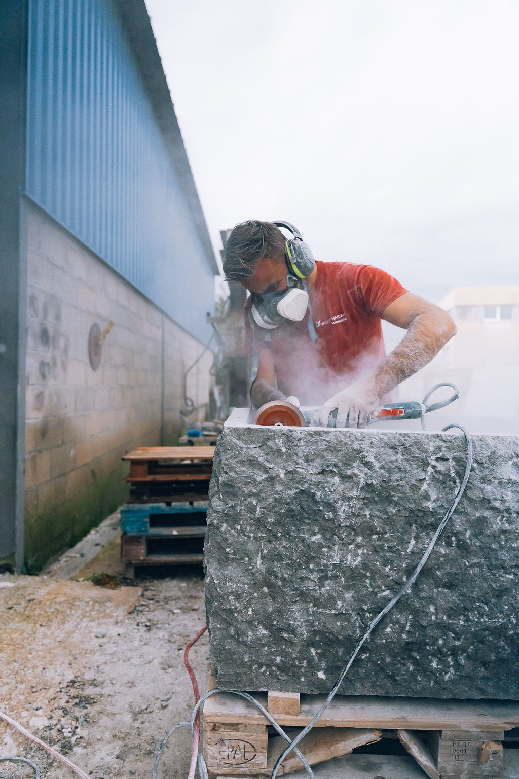Artisan tailleur de pierre façonnant une vasque en pierre naturelle brute, atelier Unique Habitat
