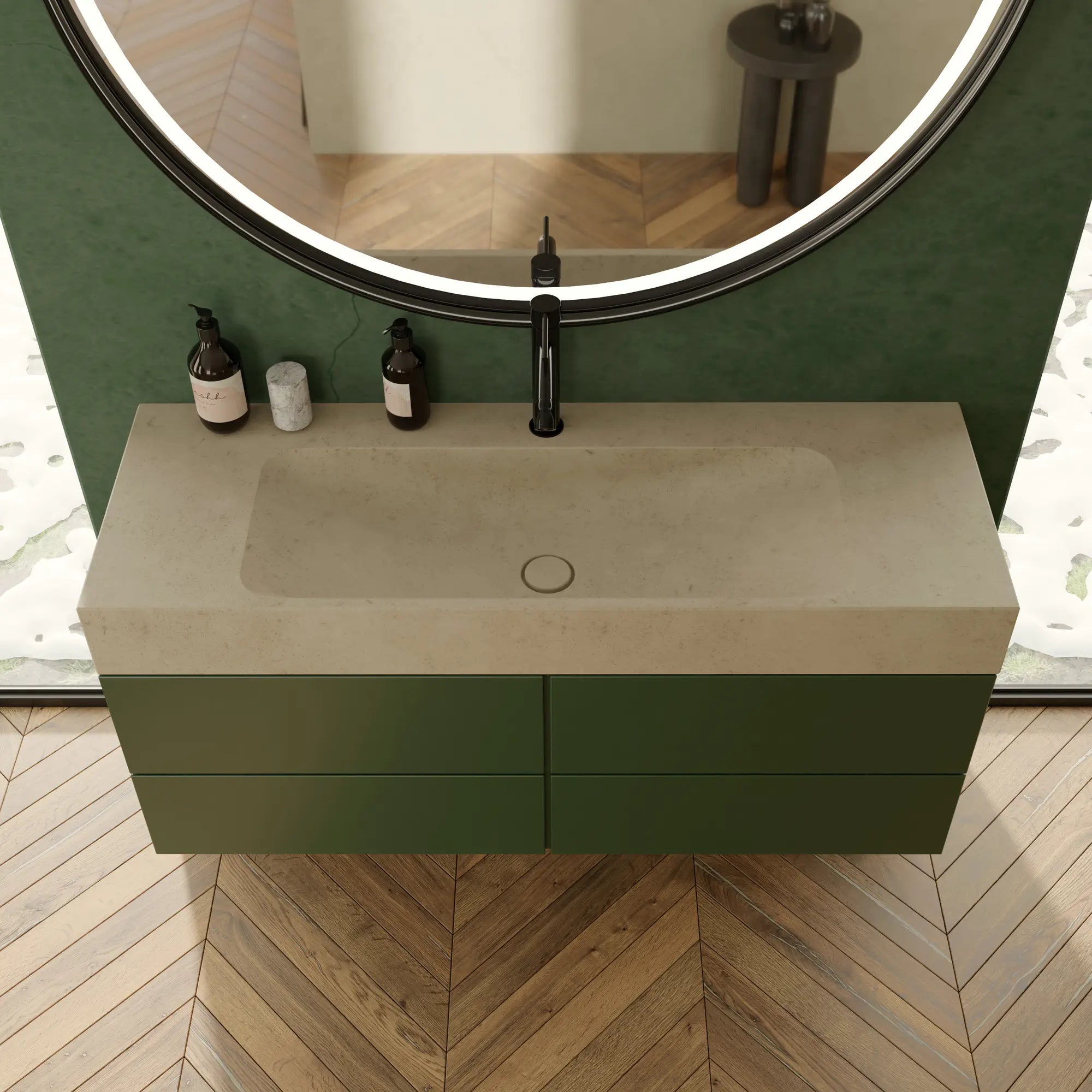  Plan de vasque minimaliste en pierre naturelle crème Moléanos, cuve intégrée rectangulaire, bonde Magique en pierre, meuble suspendu vert, robinetterie noire, miroir rond LED, mur vert et parquet chevron, salle de bain contemporaine