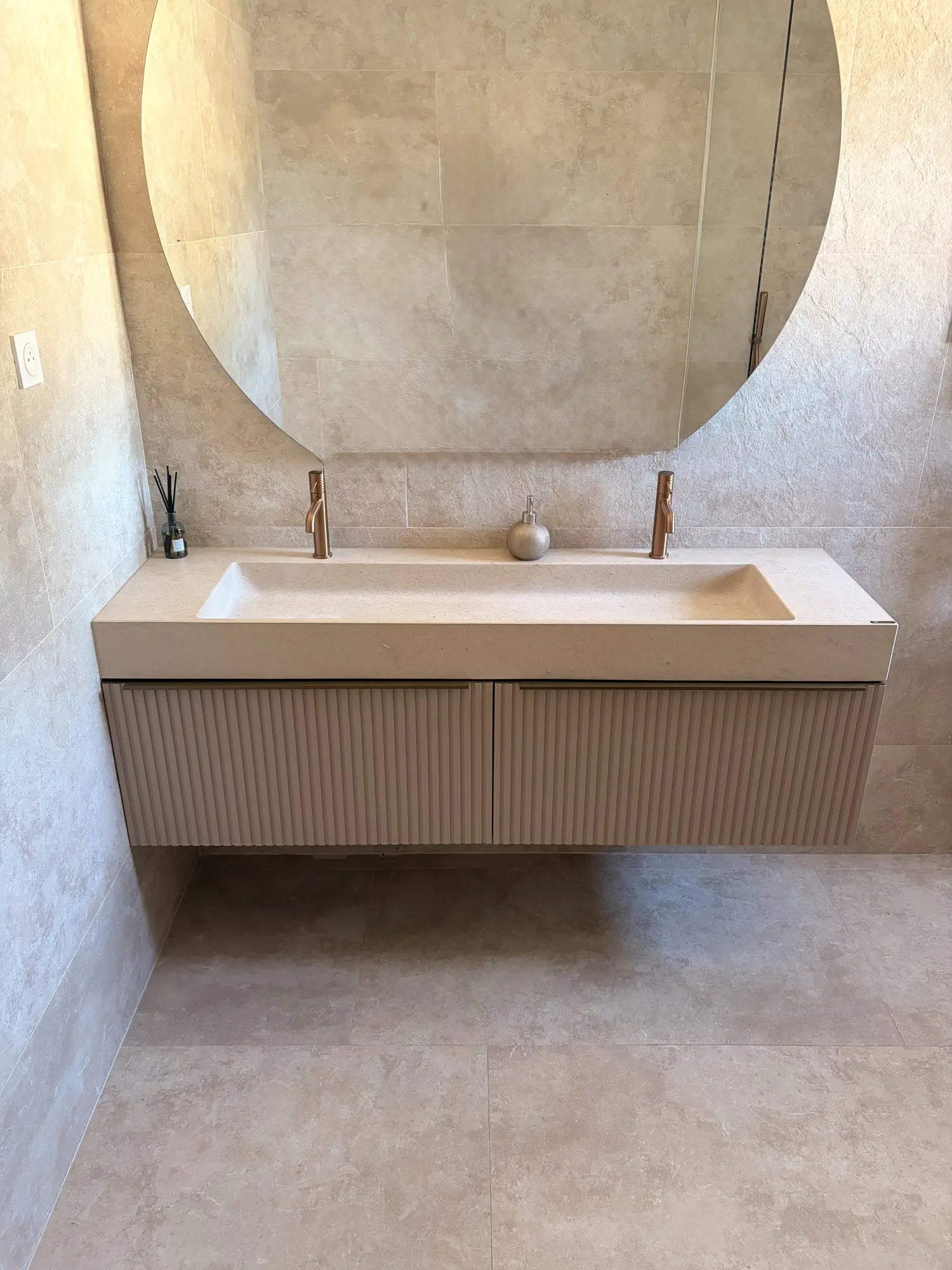 Vasque rectangulaire en pierre naturelle beige crème Moléanos, double cuve suspendue, meuble cannelé, robinetterie cuivre, grand miroir rond, salle de bain contemporaine