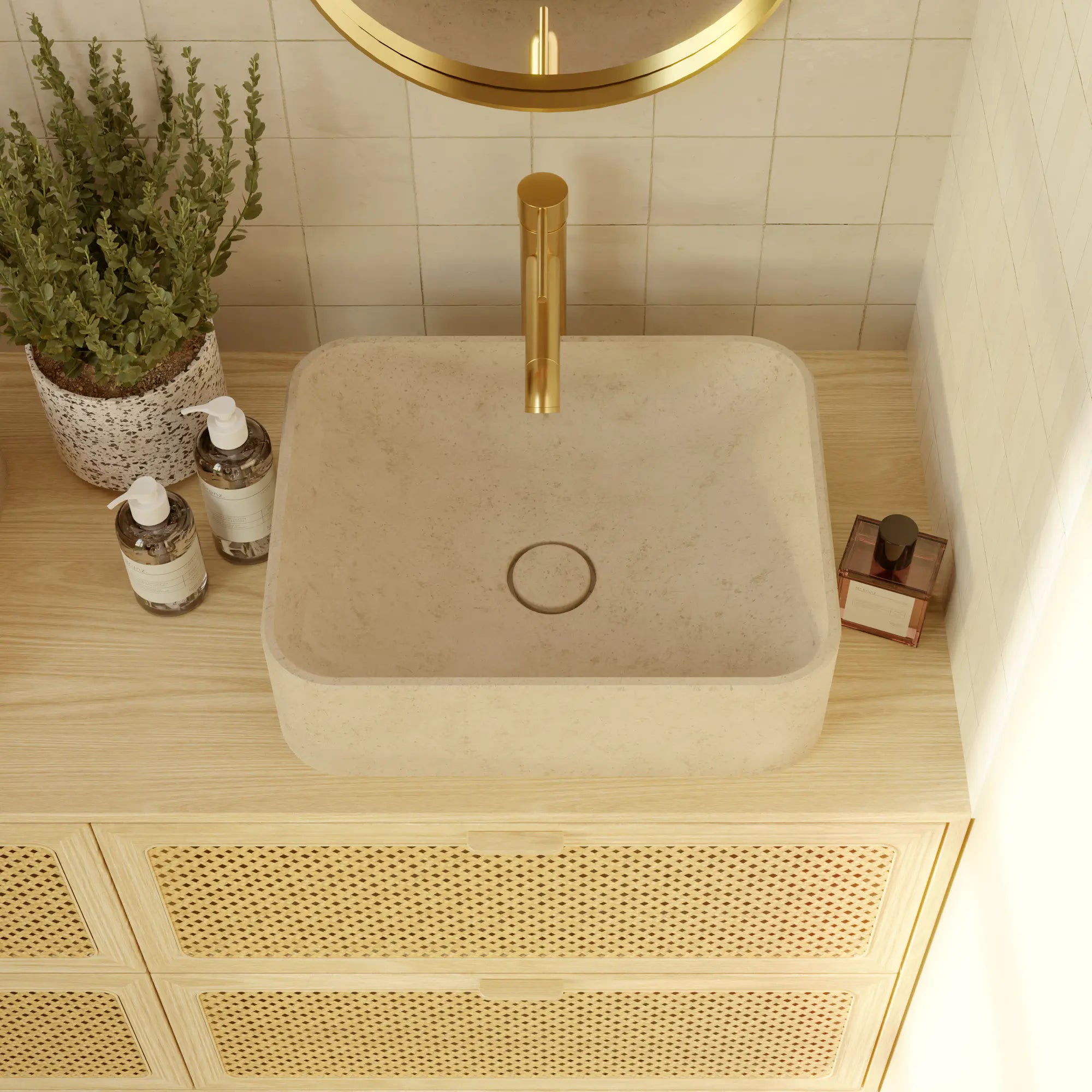 Vasque Ubaye à poser carrée en pierre naturelle crème Moléanos, bonde Magique en pierre, robinetterie dorée, miroir rond doré, meuble en bois clair et cannage, salle de bain bohème chaleureuse